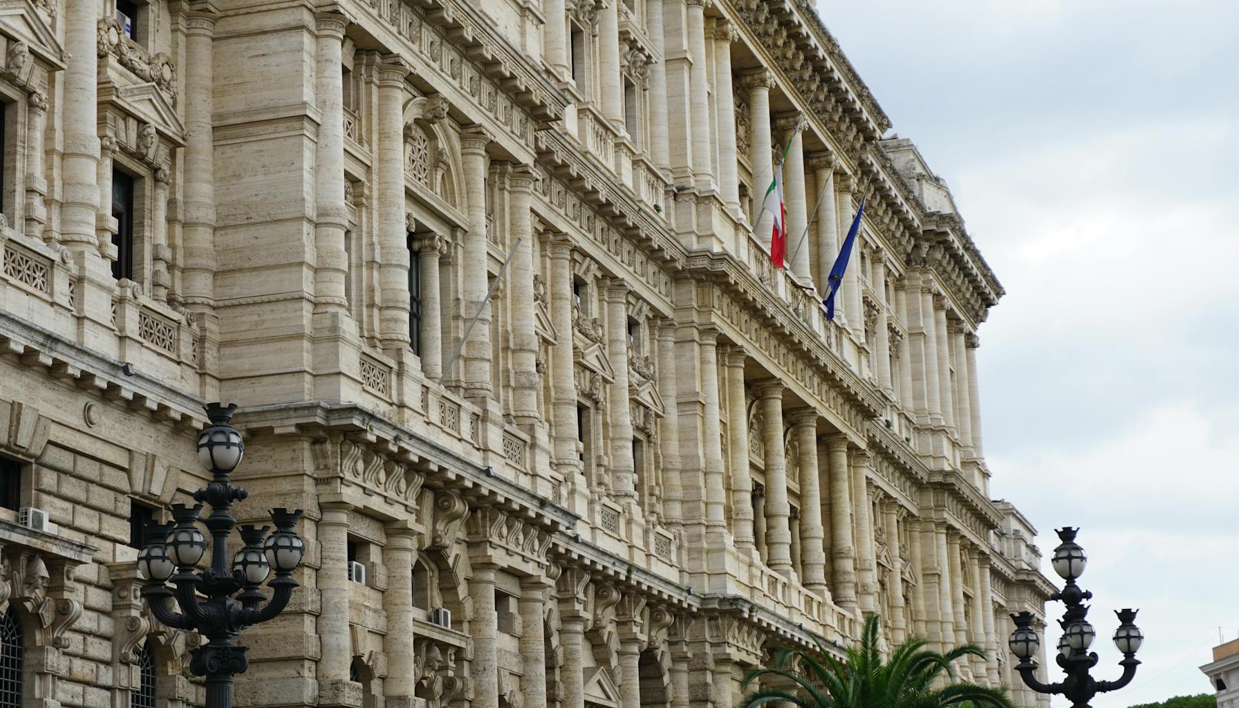 A captivating view of a neoclassical building facade in Rome with Italian flags and detailed architecture. — Foto: Babak Habibi (Pexels)
