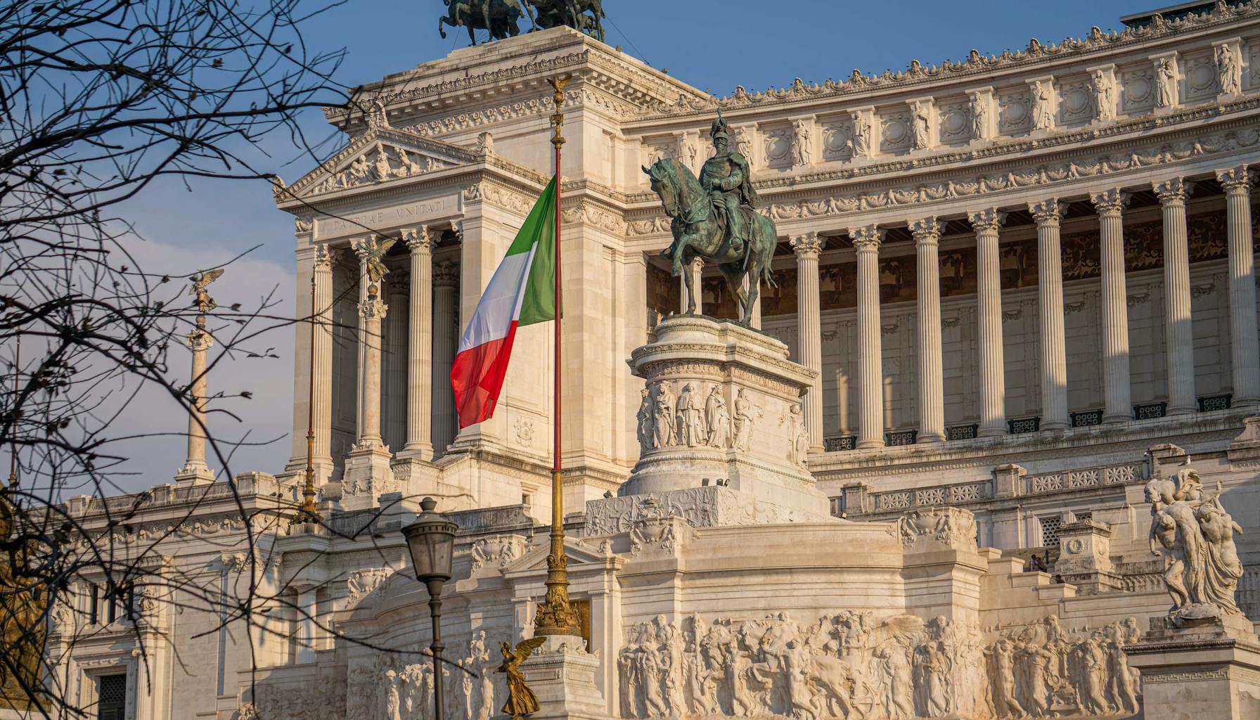The majestic Vittoriano Monument in Rome, showcasing Italian heritage with a prominent flag. — Foto: David Luyeye (Pexels)